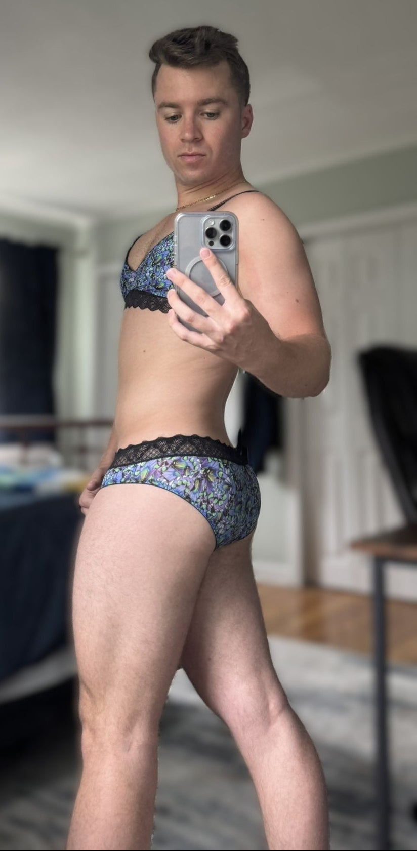 Person taking a mirror selfie wearing patterned underwear in a room.