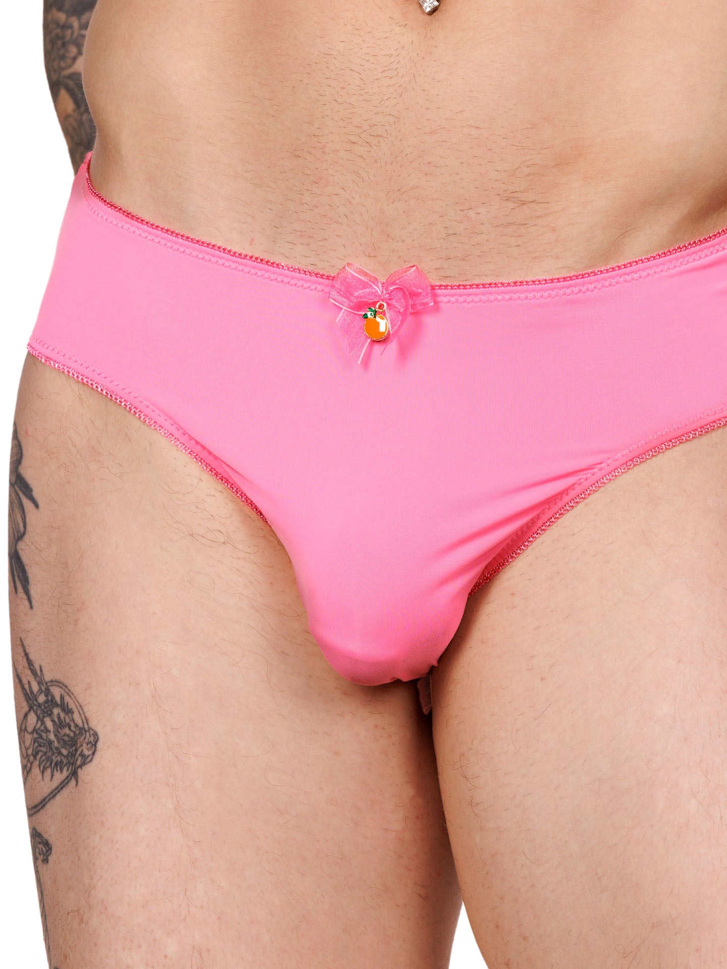 Closeup front view of a male model wearing pink hipster panties with lace trim, a matching pink bow, and a metallic orange charm.