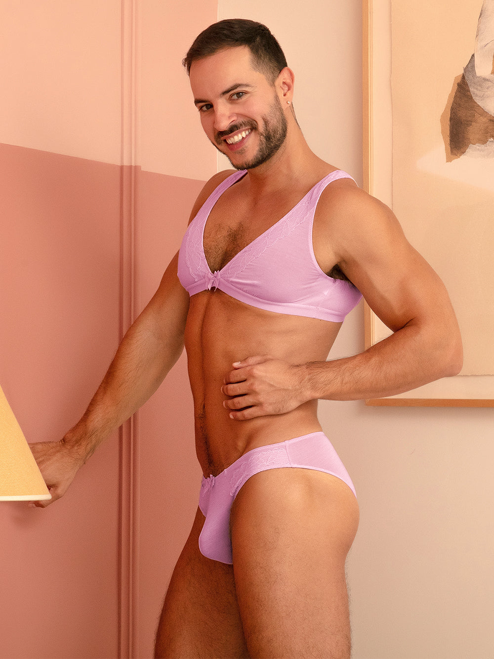 Side view of a man wearing a matching purple bra and panty set