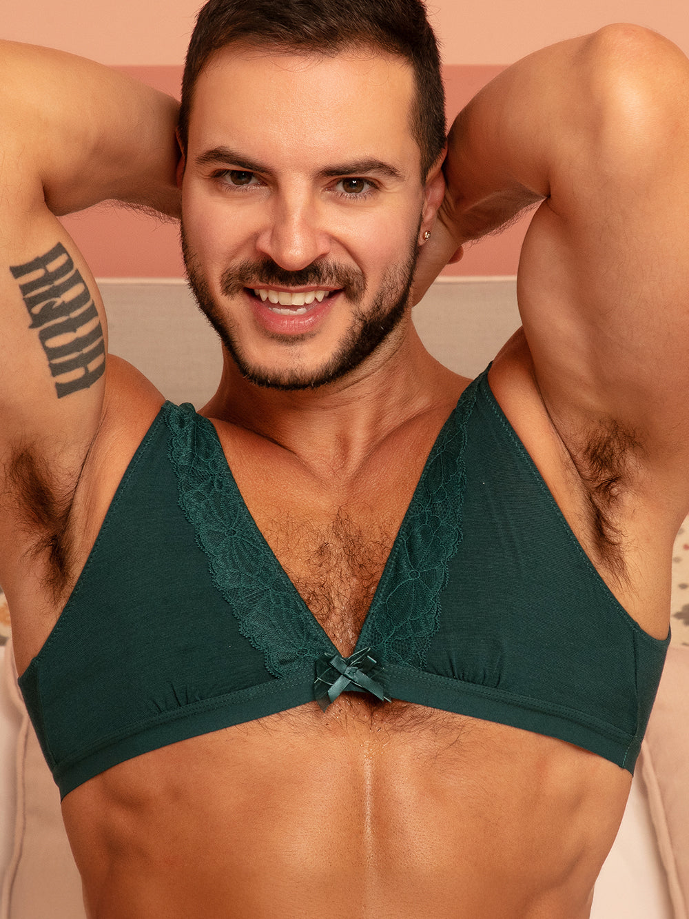 A man wearing a green bra with matching lace and bow