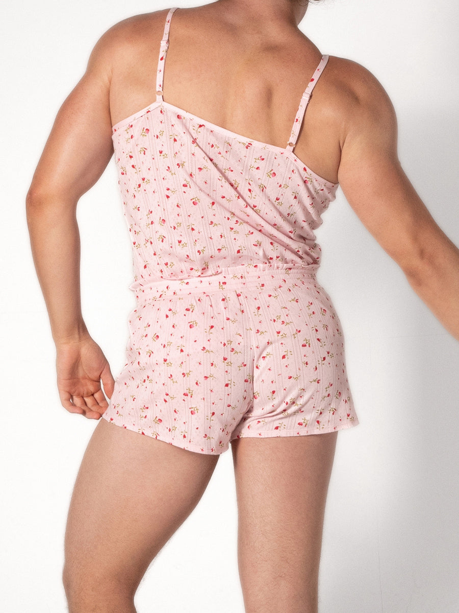 A man wearing a pink camisole with a red floral pattern and matching shorts