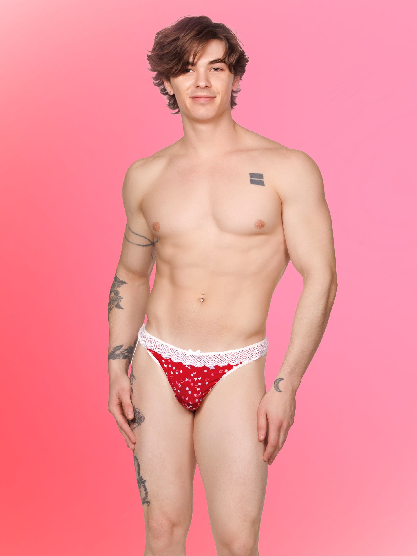 Front view of a male model wearing an XDress red and white thong with colored hearts pattern and lace waistband