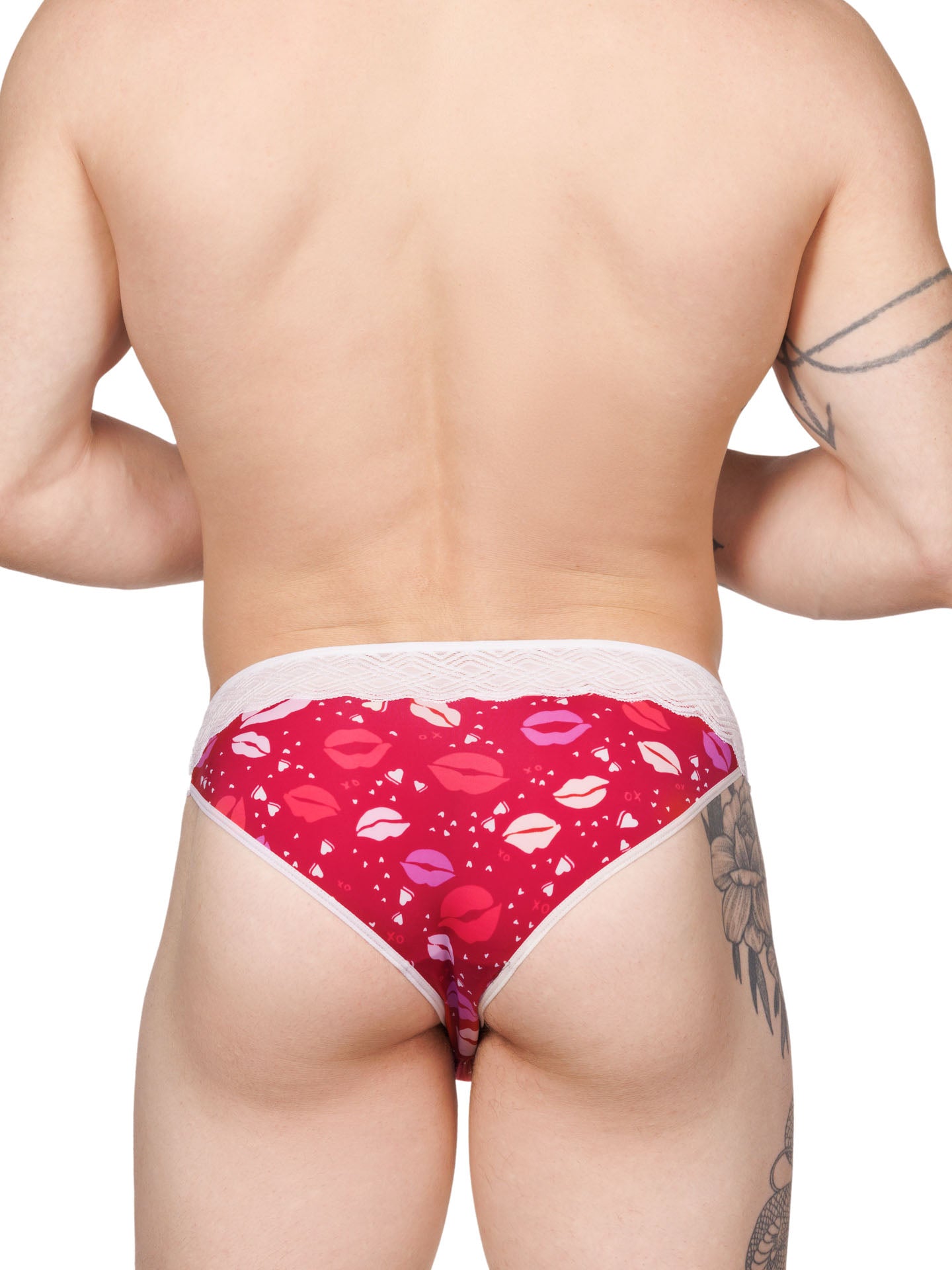 Back view of a male model wearing a red XDress men's panty with lipstick kiss pattern and lace waistband