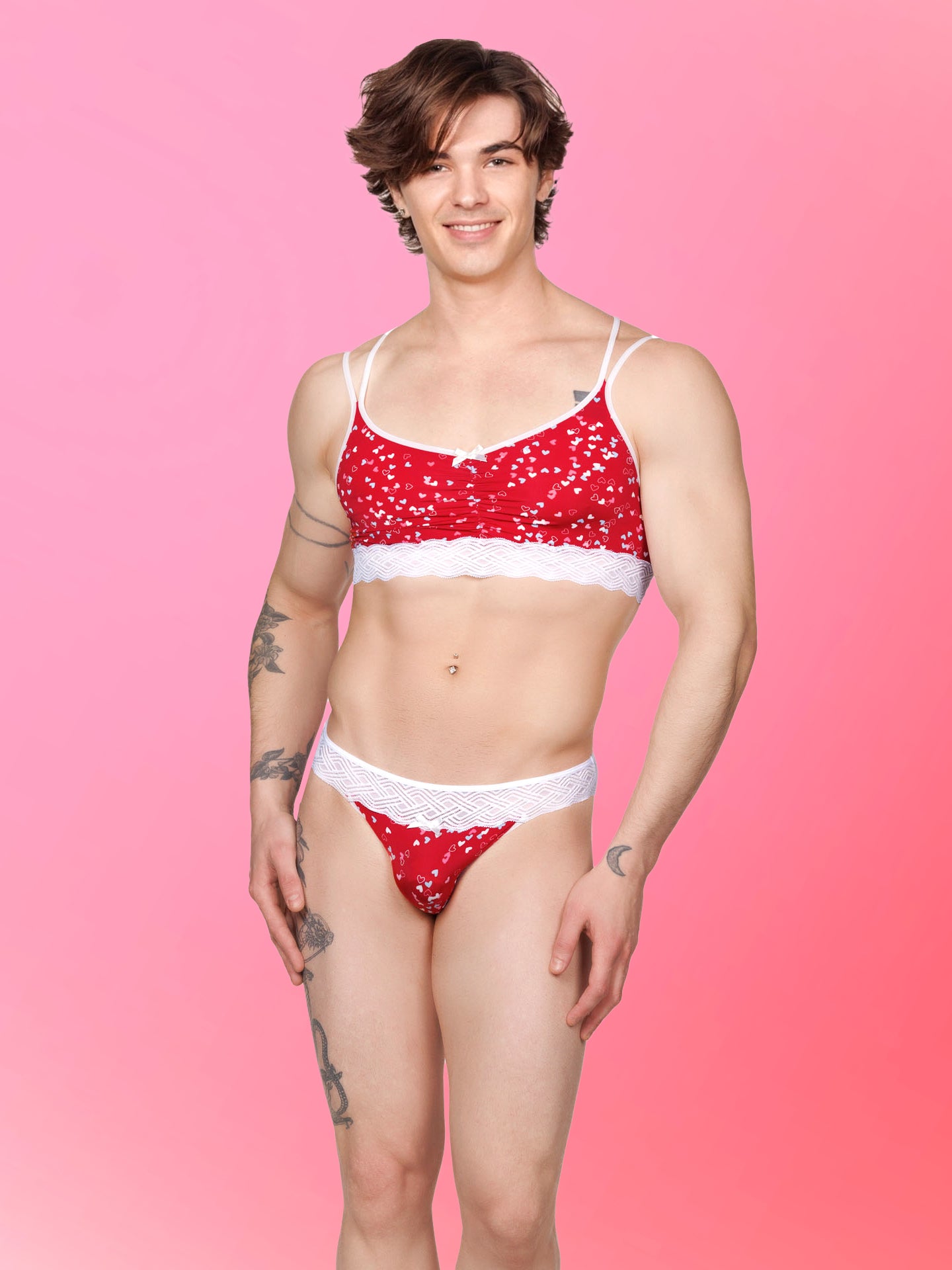 Front view of a male model wearing an XDress matching red men's panty and bra with white hearts pattern and lace waistband