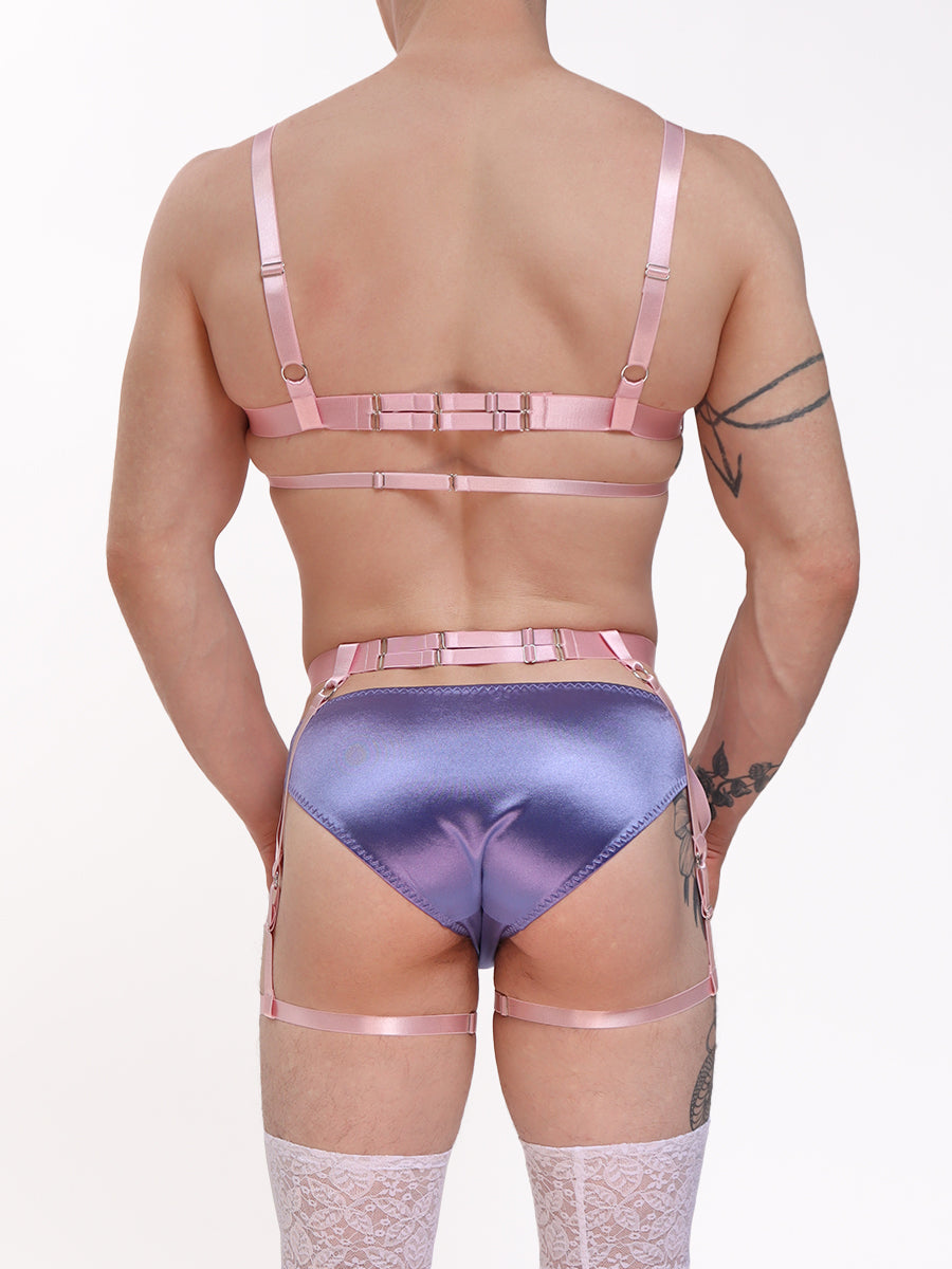 Back view of a male model wearing a pink strappy harness with purple XDress lingerie underneath